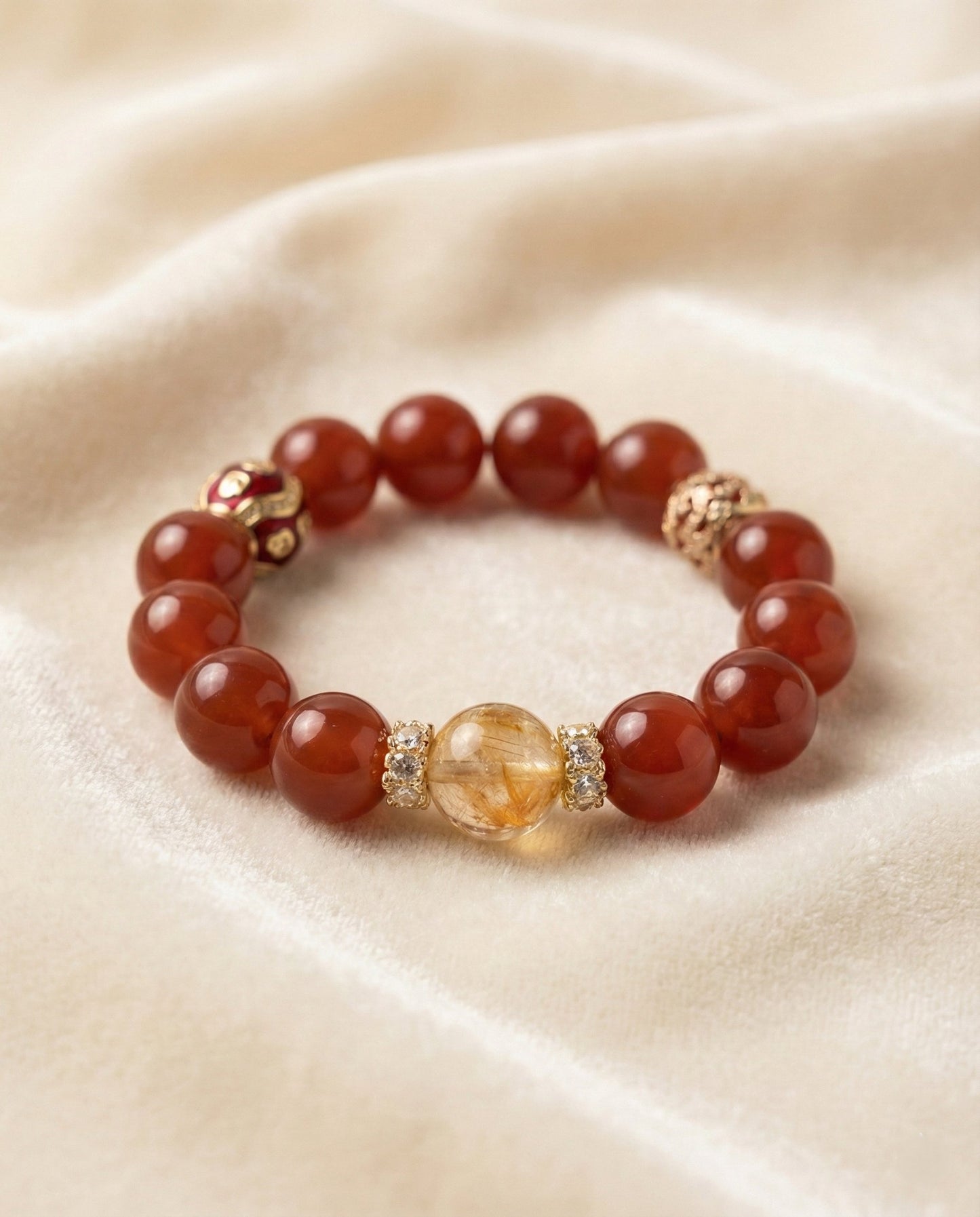 The Vermilion Fortune Bracelet, shown at a gentle angle on a light velvet surface.