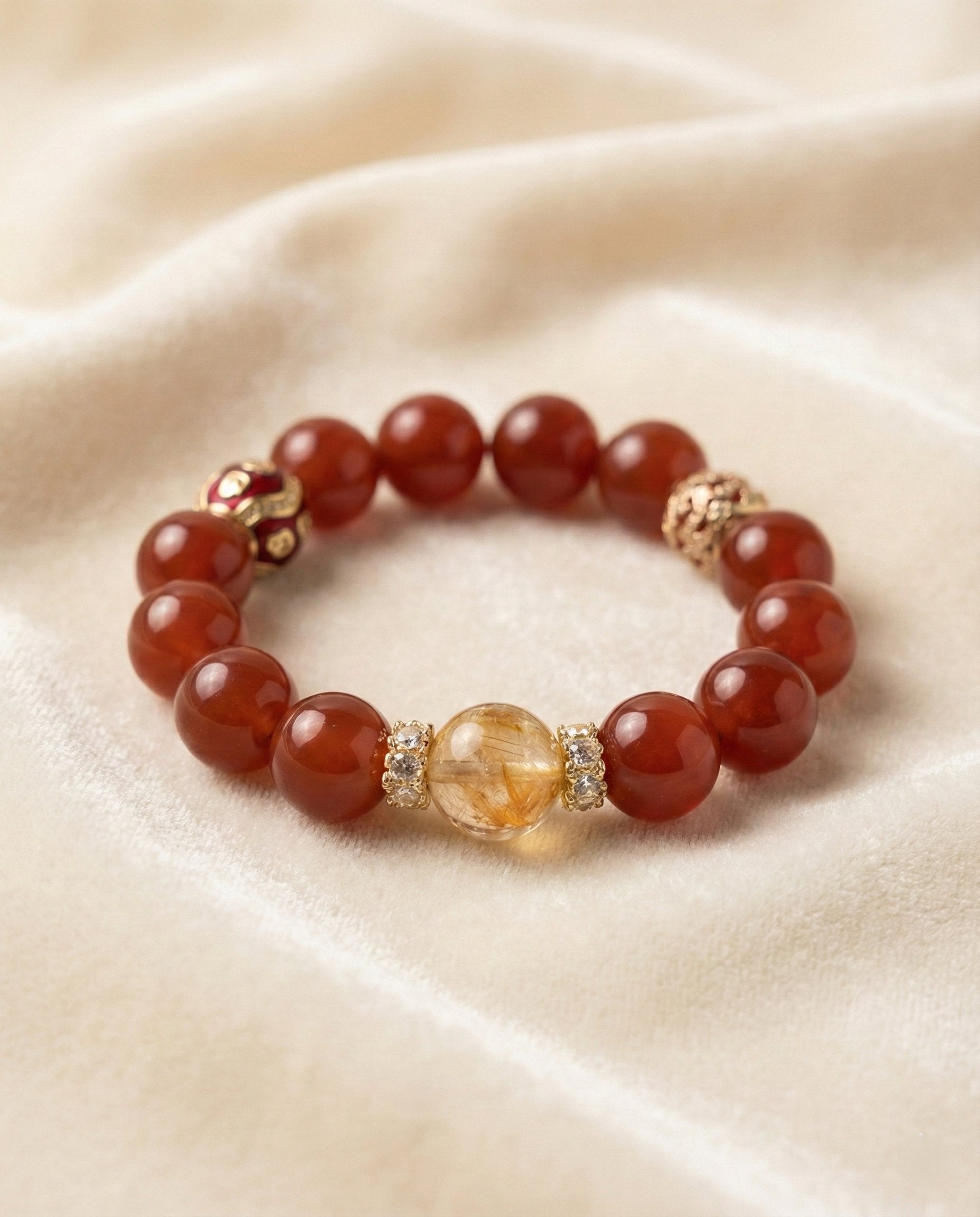 The Vermilion Fortune Bracelet, shown at a gentle angle on a light velvet surface.